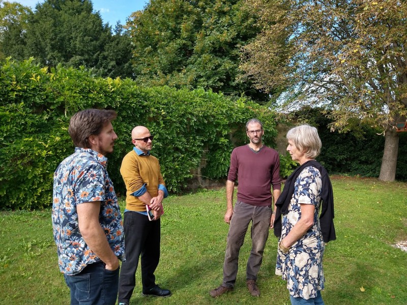 A group of people standing in a grassy area with trees in the backgroundDescription automatically generated with medium confidence